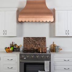 a stove top oven sitting inside of a kitchen under a copper hood over it's burner