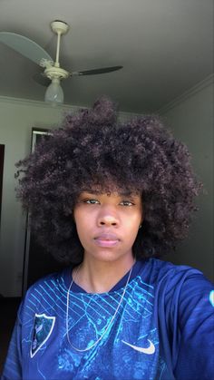 a woman with an afro is taking a selfie in front of a ceiling fan