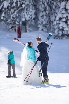 a bride and groom are standing in the snow with skis on their back legs