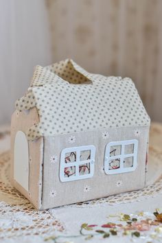 a doll house sitting on top of a table next to a flowery doily