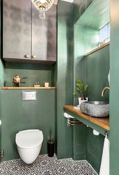 a bathroom with green walls and black and white floor tiles on the floor, along with a toilet and sink