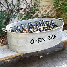 a metal tub filled with beer bottles sitting on top of a wooden bench