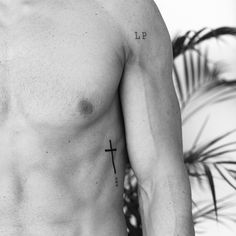 a shirtless man with a cross tattoo on his left chest and the word lp written in black ink