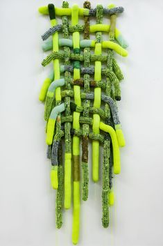 an art piece made out of green and yellow pipes on a white surface with wires attached to it