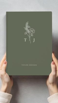 a person holding up a book with the letter j on it's front cover