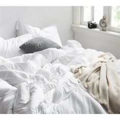 an unmade bed with white sheets and pillows