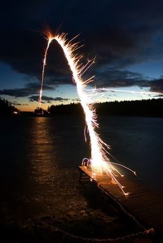 a long exposure photograph of fireworks on the water at night time, with dark clouds in the background