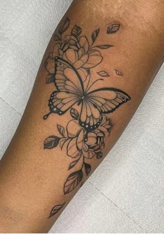 a woman's arm with a butterfly and flowers tattoo on the left side of her leg