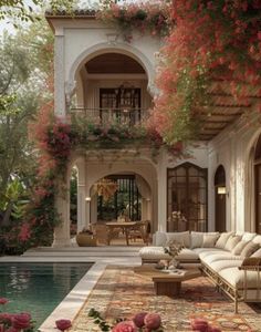 an outdoor living room and pool area with flowers growing on the walls, furniture in the foreground