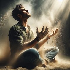 a man sitting in the sand with his hands up and eyes closed, while praying