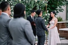 a bride and groom standing at the alter during their wedding ceremony in front of an arch decorated with white flowers