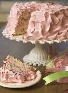 a cake with pink frosting and sprinkles sitting on top of a table