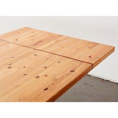 a wooden table with no one sitting at the top in front of it and a wall behind it