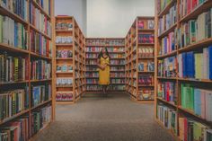 a woman standing in the middle of a library filled with books