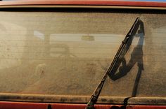 the shadow of a person is seen on the windshield of a car with a long stick sticking out of it