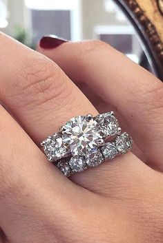 a woman's hand with two diamond rings on her wedding ring and the other one has