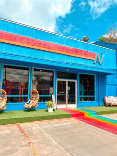 a brightly colored building with lawn chairs in front