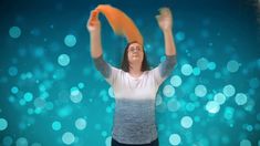 a woman is holding an orange frisbee in front of her head and arms