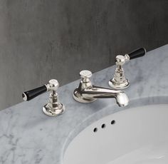 two chrome faucets sitting next to each other on a marble counter top in a bathroom