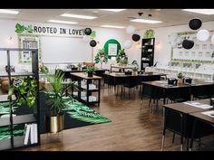 a room with tables, chairs and plants on the wall in front of it that says rooted in love