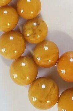 a group of yellow beads sitting on top of a white table next to each other