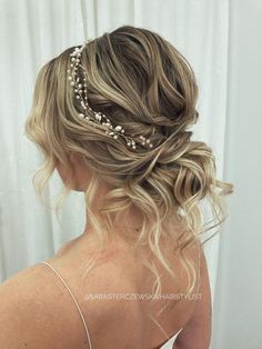 a woman with blonde hair wearing a braid and pearls in her hair is looking into the mirror