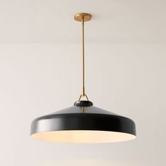 a black and gold pendant light hanging from a ceiling in a room with white walls