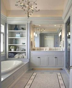 a large bathroom with white cabinets and a chandelier above the bathtub is shown