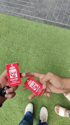 two people holding up red cards in front of each other on green grass with stairs behind them