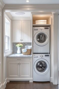 a washer and dryer in a white laundry room with wood flooring, built - in cabinetry, and marble counter tops