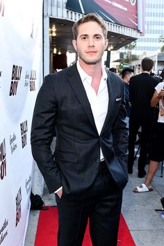 a man in a suit standing on a red carpet