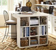 a book shelf with many books on top of it next to a chair and table