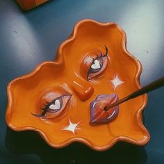 a yellow bowl with two eyes painted on it and a pair of scissors in the middle