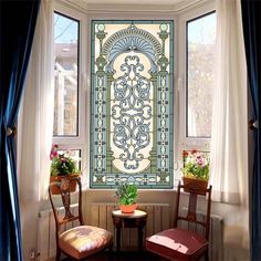 two chairs and a table in front of a stained glass window with potted plants