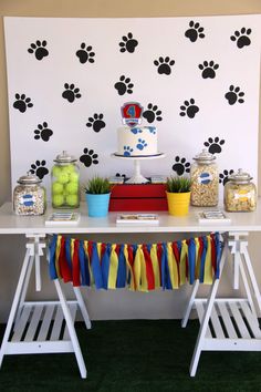 a dog themed birthday party with decorations and food on the table, including an animal paw print wallpaper