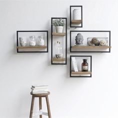 three shelves with books, vases and other items on them against a white wall