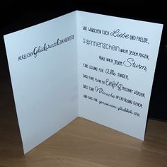 an open white card with black writing on the front and back side, sitting on a wooden table