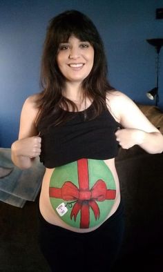 a pregnant woman wearing a black top with a red bow on it's belly