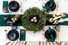 the table is set for christmas dinner with green and gold decorations