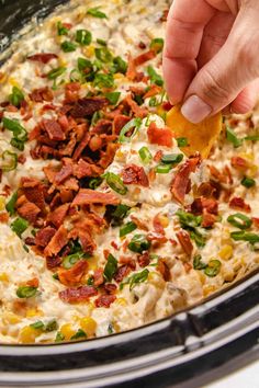 a person is dipping some food into a crock pot filled with corn and bacon