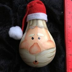 a brown and white vase with a santa hat on it next to a measuring ruler