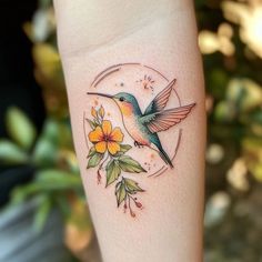 a hummingbird on the arm with flowers around it