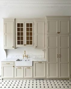 an empty kitchen with white cabinets and black and white floor tiles on the floor,