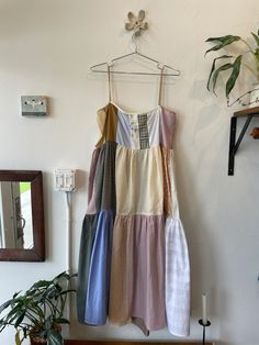 a dress hanging up on a wall next to a potted plant in a room