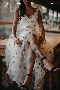 a woman sitting on top of a wooden bench wearing a dress with stars all over it