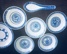 six blue and white plates with spoons on top of each one in the shape of a dragon