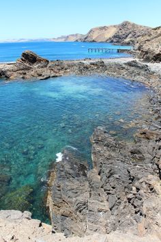 the water is crystal clear and blue in this rocky beach area with large rocks on both sides