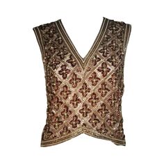 This Galanos blouse is composed of a beaded and sequin appliqued silk, in gold and burgundy hues. The top features a 3-dimensional beading technique. There are center back hook and eye closures. In excellent condition. **Please cross-reference measurements for personal accuracy. Measurements (Approximately) Length: 19" Bust: 36" Waist: 34" Luxury Embellished Fitted Top, Brown Sleeveless Evening Tops, Hand Embellished Fitted Top For Party, Silk Embroidered Evening Tops, Glamorous Embroidered Party Tops, Festive Fitted Hand Embellished Tops, Fitted Hand Embellished Tops For Festive Occasions, Elegant Embellished Embroidered Top For Party, Glamorous Hand Embellished Tops For Party