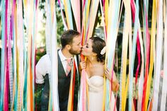 a bride and groom kissing in front of streamers