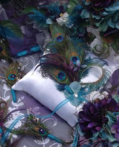 peacock feathers on a pillow and some purple flowers